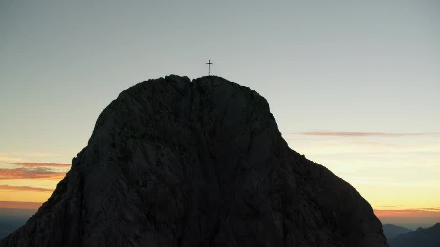 Cross on top of a mountain at sunrise
