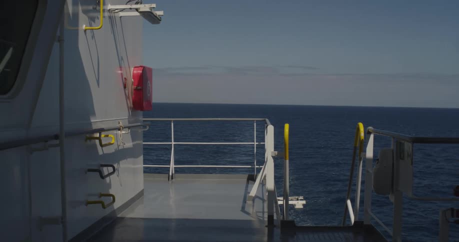 A serene view from the deck of a ship as it sails across the vast, calm blue ocean on a clear day
