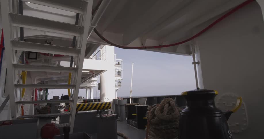 Static view from the shaded deck of a large vessel sailing on the calm open sea