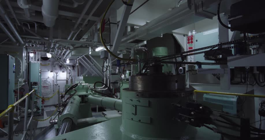 Wide interior shot of the complex mechanical systems and engine components inside a large vessel's engine room