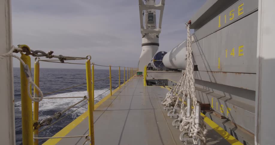 A static view from the walkway of a large industrial vessel as it travels across the open ocean