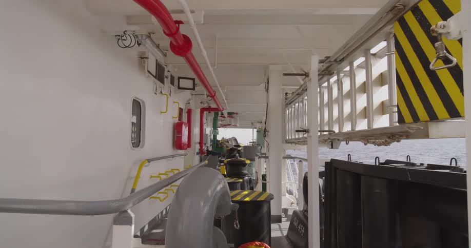 A static shot of an industrial walkway on the deck of a large vessel as it sails across the open ocean