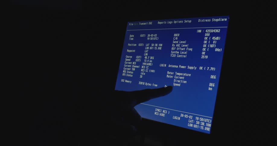 A silhouetted hand points to navigational and system data displayed on a classic blue computer monitor in a dark room