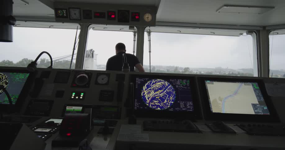 Slowly pulling back from a ship's advanced control panel as a captain stands at the window of the bridge