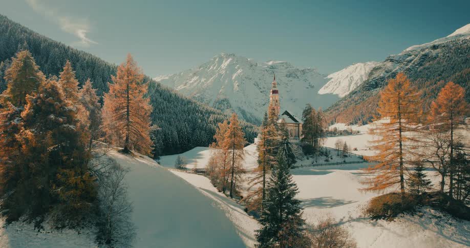 A stunning time-lapse shows a picturesque church in a mountain valley as the season transitions from a sunny autumn day to a snowy winter wonderland