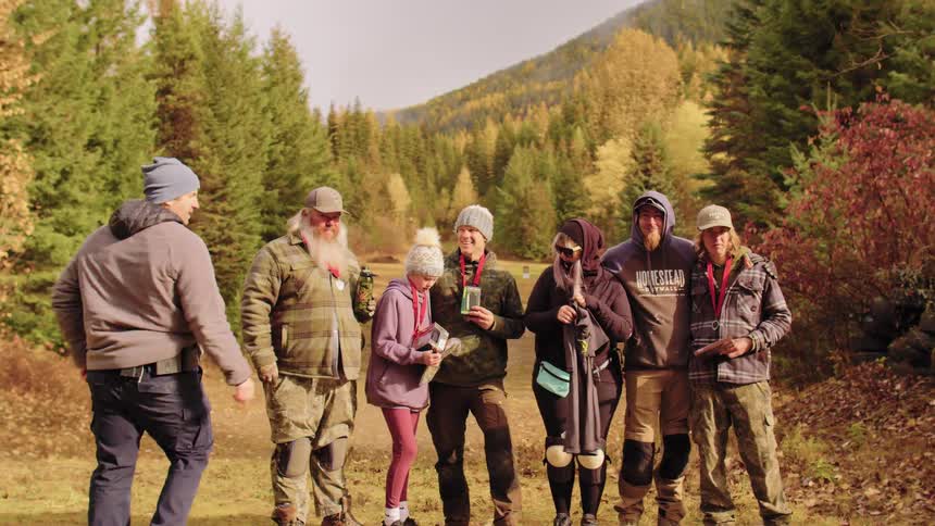 A group of happy competitors pose for a celebratory photo with their awards at an outdoor shooting range in the autumn forest