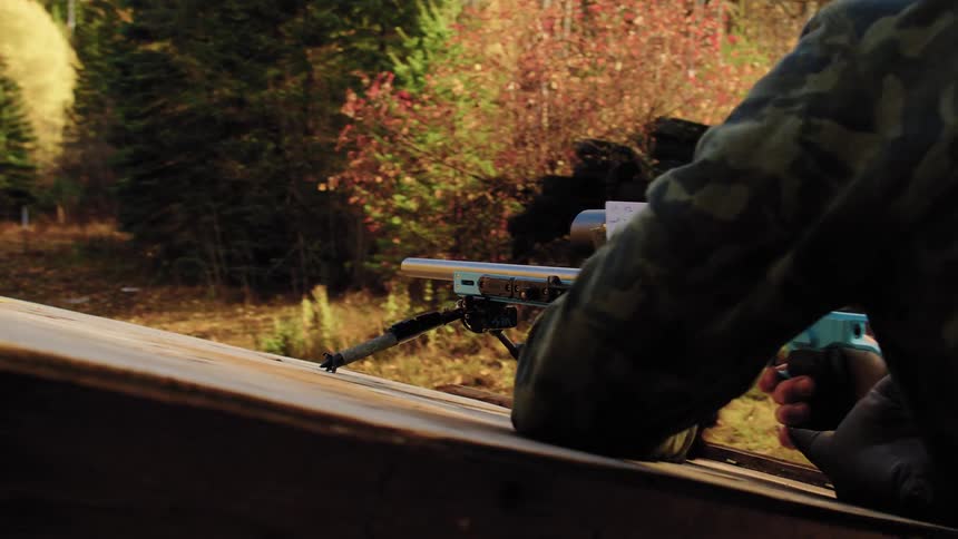A focused shooter in a beanie aims a high-precision rifle downrange before quickly moving to a new prone position