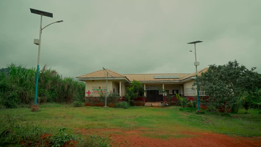 A rural health clinic in Africa is powered by solar panels and flanked by solar streetlights on a cloudy day