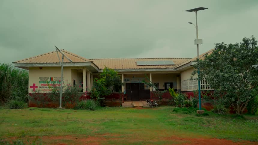 Wide exterior shot of a solar-powered health clinic in a rural African community on an overcast day