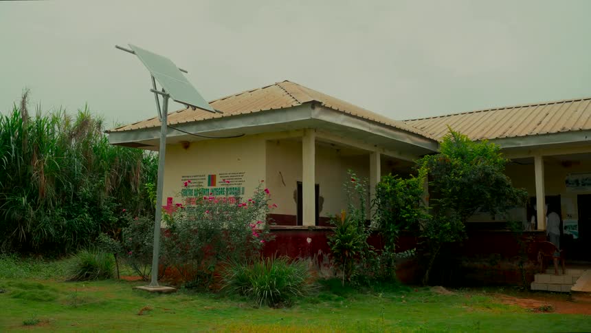 A solar panel provides clean, renewable energy to a rural building surrounded by lush green vegetation