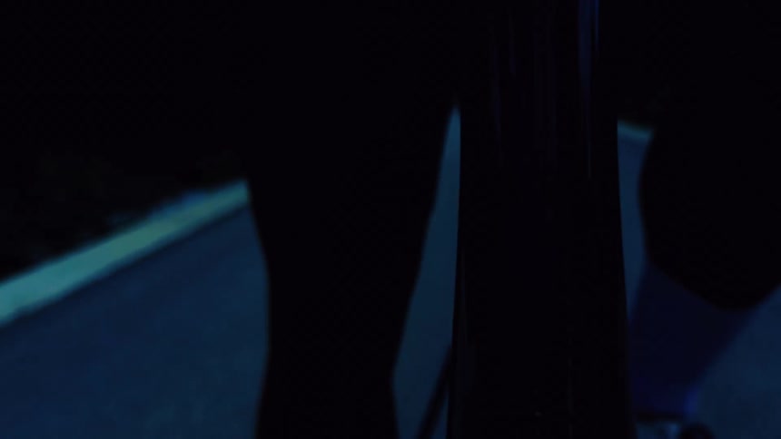 Close-up of a person's legs and feet pedaling a bicycle on a dark road at night