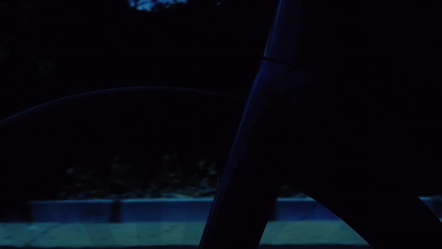 A dark, silhouetted view from inside a moving car looking out the passenger window at the passing scenery at night