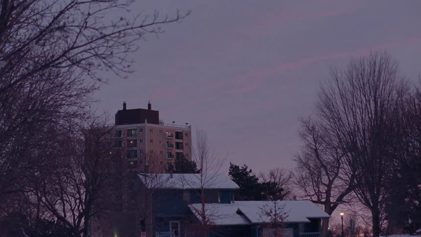 A quiet winter neighborhood scene transitions from dusk into night in this peaceful timelapse