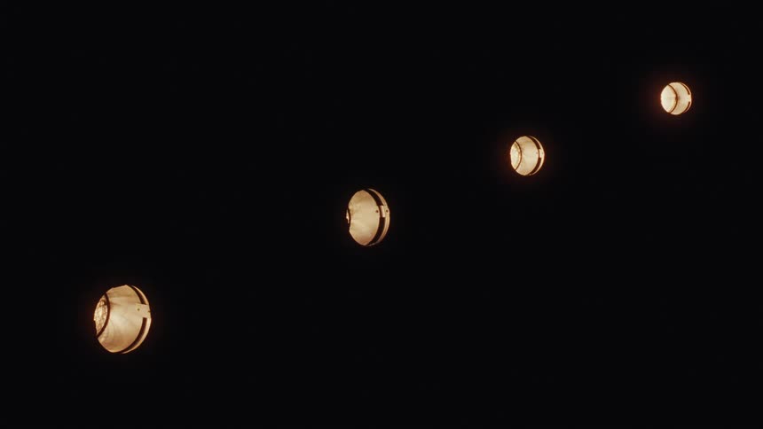 A diagonal row of four recessed ceiling lights turn on sequentially in the dark