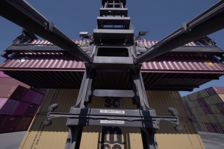 POV from a container handler as it lowers a large shipping container onto a stack in a busy port yard