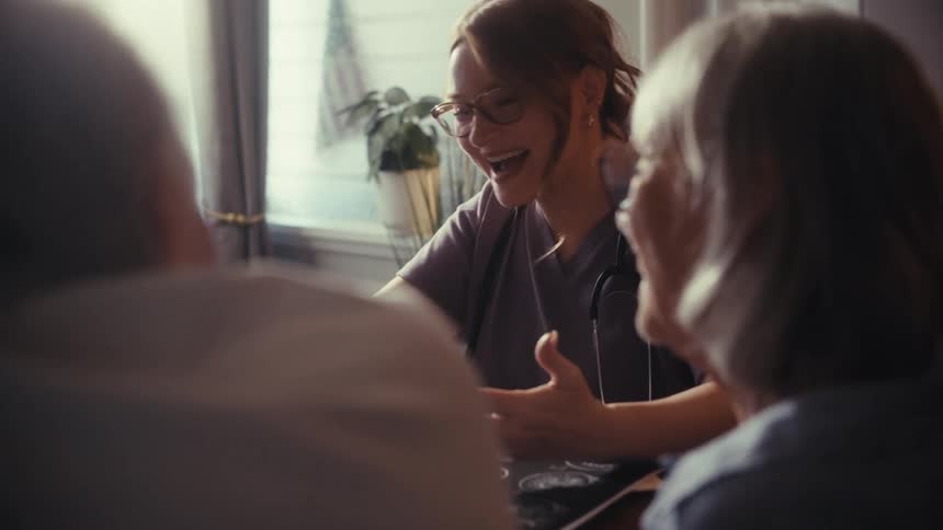 A compassionate doctor shares positive medical results with a smiling senior couple during a home visit