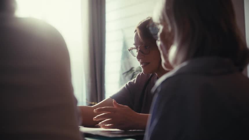 A caring female doctor consults with a senior couple during an in-home visit, explaining medical information