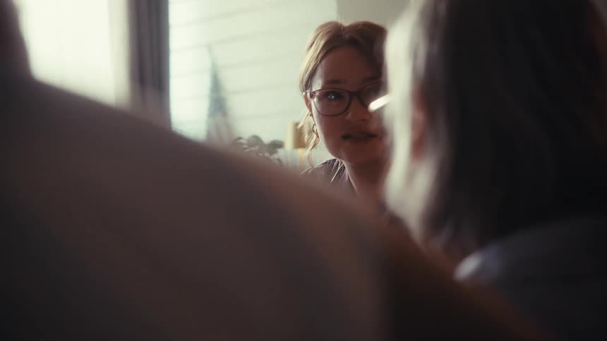 A compassionate female healthcare provider explains a diagnosis to an elderly couple during a home visit