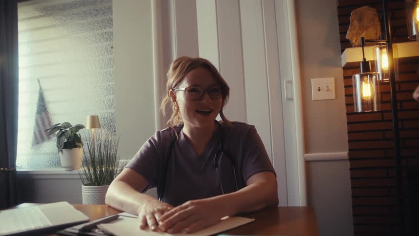 A compassionate home healthcare nurse smiles warmly while consulting with an elderly couple at their dining table