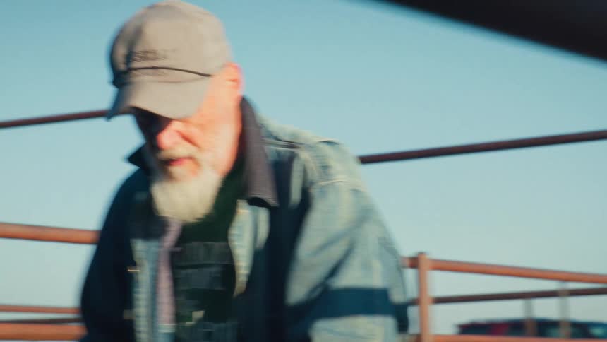 An older farmer with a long white beard works hard on the farm in a cinematic slow-motion close-up