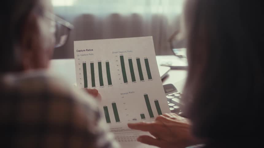 Close up over the shoulder shot of a senior couple analyzing financial performance charts and graphs