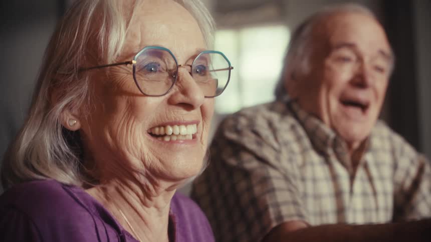An elderly couple expresses joy and relief as they shake hands with a consultant after a successful meeting