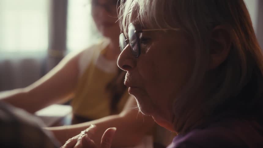 An elderly woman in glasses thoughtfully discusses important family matters with her husband and daughter