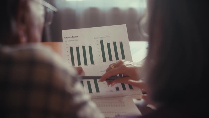 An over-the-shoulder shot of a senior couple reviewing financial charts and planning for their retirement