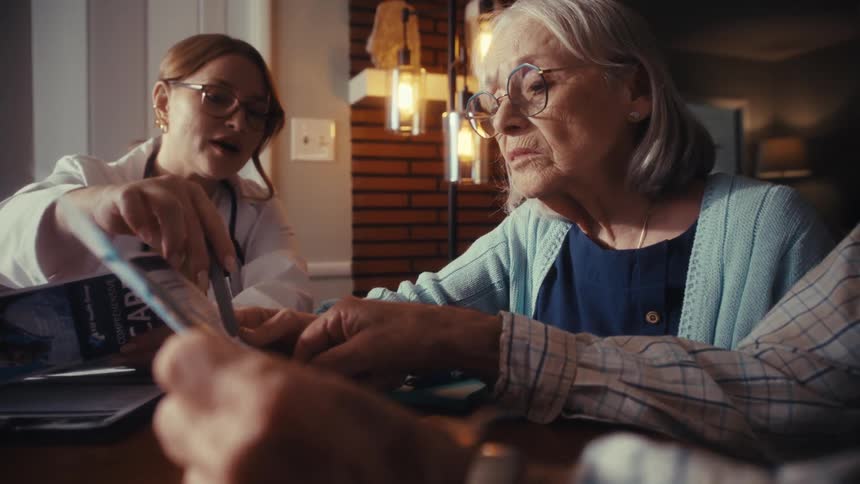 A caring female physician discusses medical options with a senior couple in their home using a brochure