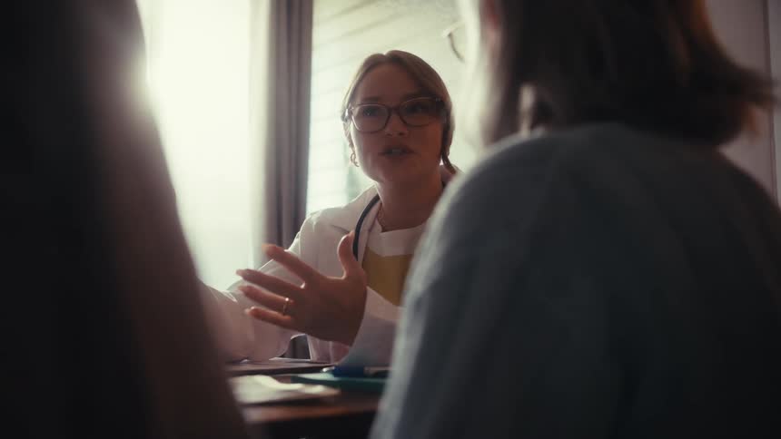 A compassionate female doctor in her office explains medical results to her patients in slow motion