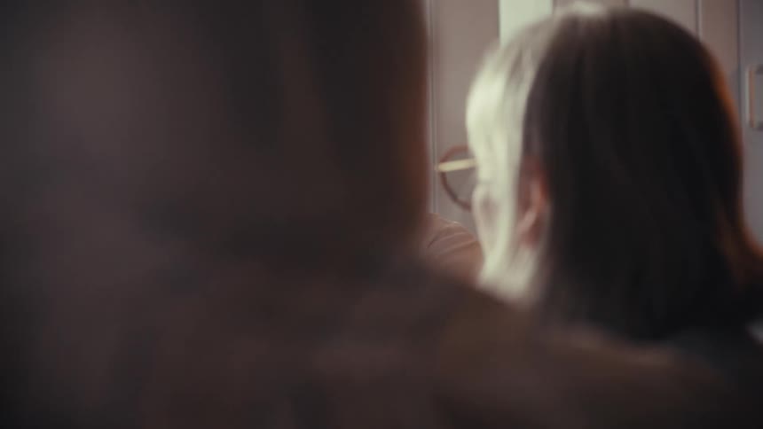 A young female doctor wearing a lab coat and stethoscope consults with an elderly couple in her sunlit office