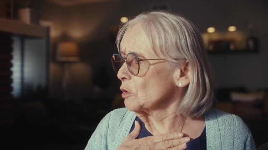 A concerned senior woman and her husband listen as a doctor explains a diagnosis, with a slow zoom into the woman's shocked expression