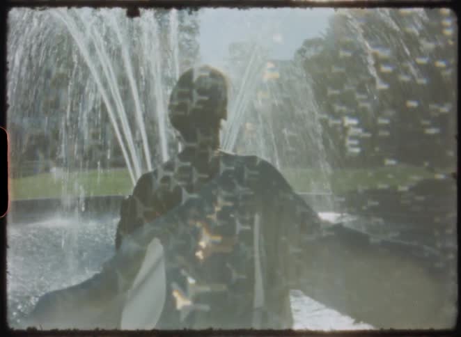 Abstract and surreal vintage footage captures a statue in a glistening water fountain on a sunny day