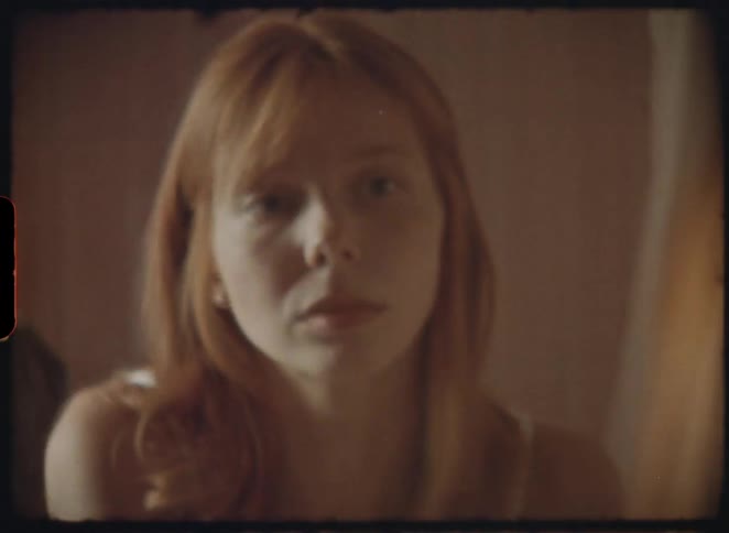 Super 8 style mirror reflection of a man filming an intimate portrait of a woman in a bathroom