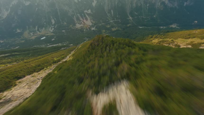 A thrilling high-speed FPV drone dive down a lush, rocky mountain ridge towards the valley below