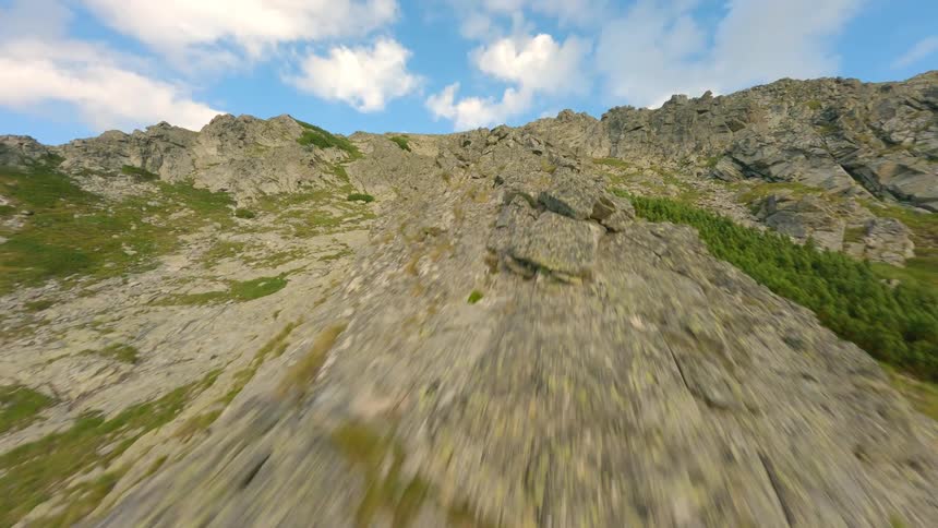 Epic fast paced aerial pullback over a rugged mountain ridge with a beautiful blue sky