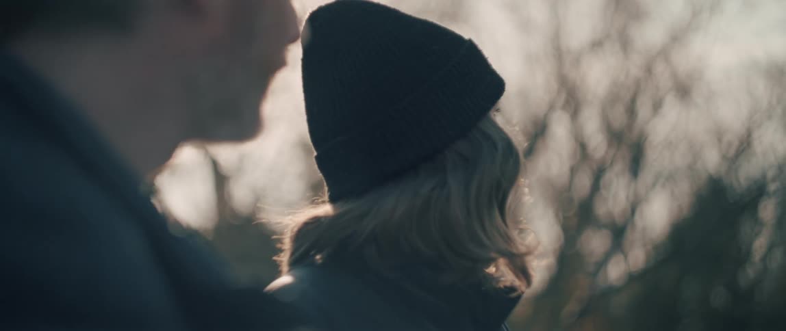 A dreamy slow-motion close-up of a couple enjoying a quiet, intimate moment outdoors with bright lens flare