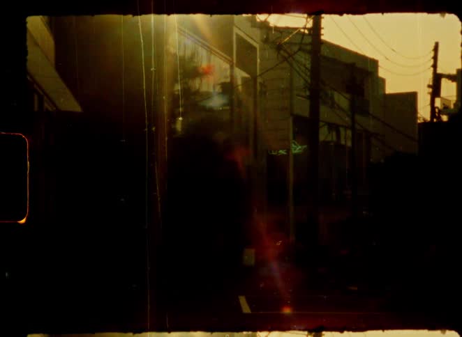 Vintage 8mm film captures contrasting scenes of a shadowy Japanese city street and a serene forest Torii gate