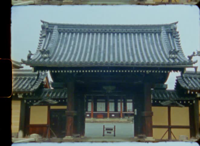 Vintage 8mm film footage zooms out through the wooden gate of a traditional Japanese temple