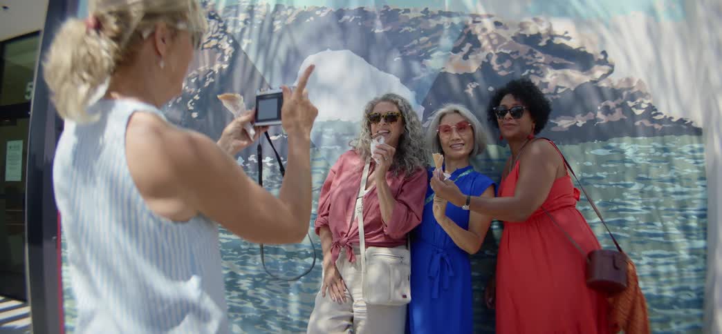 A group of senior female friends happily pose for a photo with their ice cream cones on a sunny summer vacation