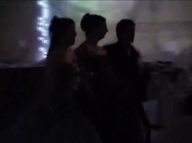Grainy vintage footage captures the silhouettes of high school students dancing at a dimly lit prom