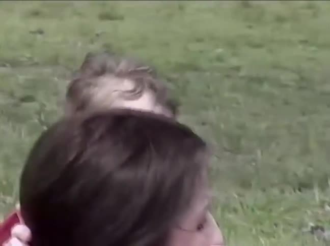 A young boy runs crying to his mother for comfort while playing at the park on a sunny day
