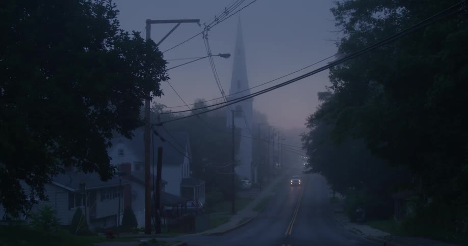 Cars driving through a small town on a foggy day