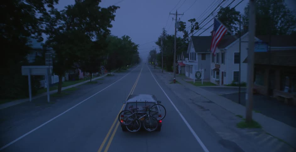An suv carrying bicycles drives along a village road