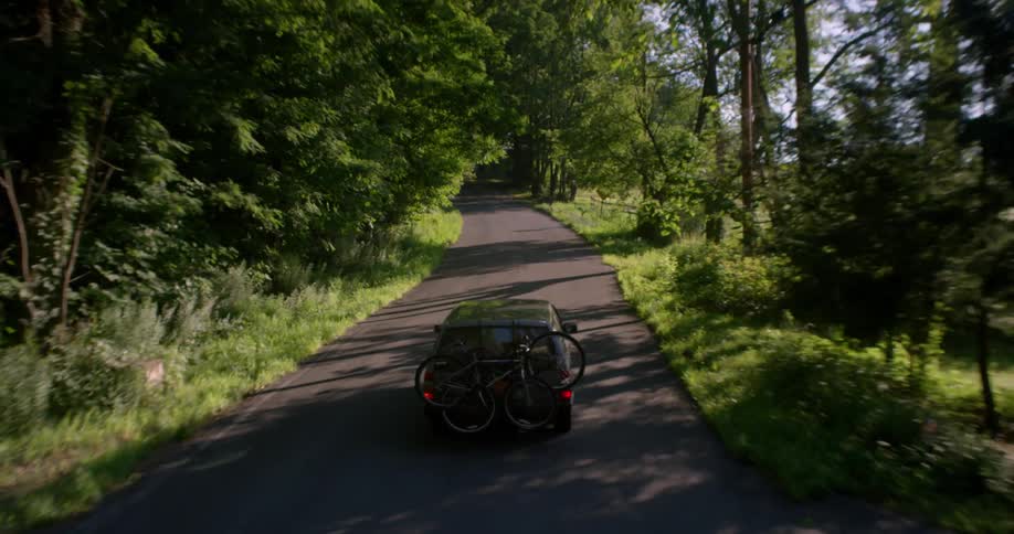 A car is driving on a small road in the woods