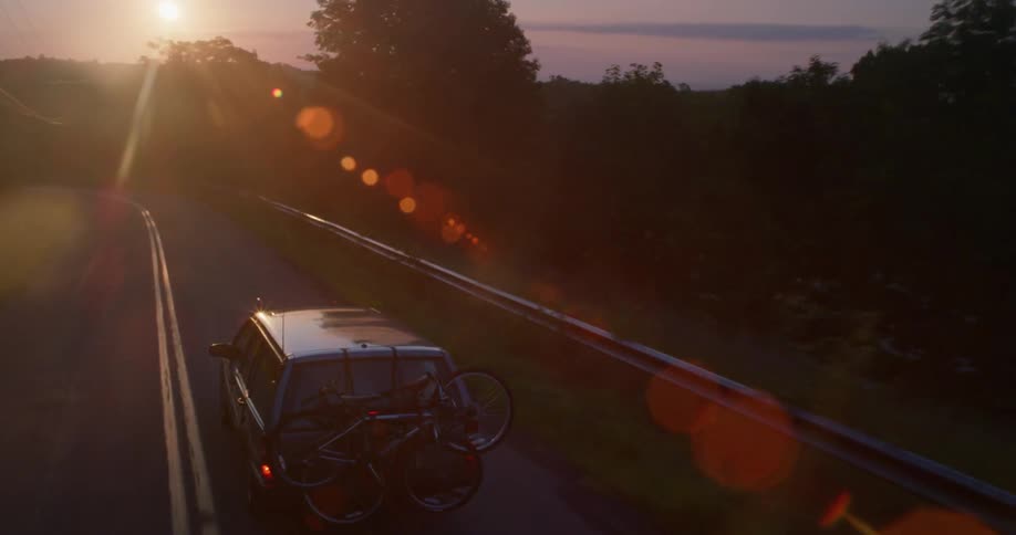 A car drives down a highway toward the sun