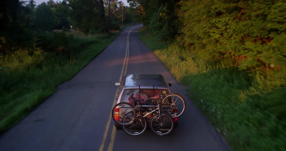 A car hauls bicycles through a forested area