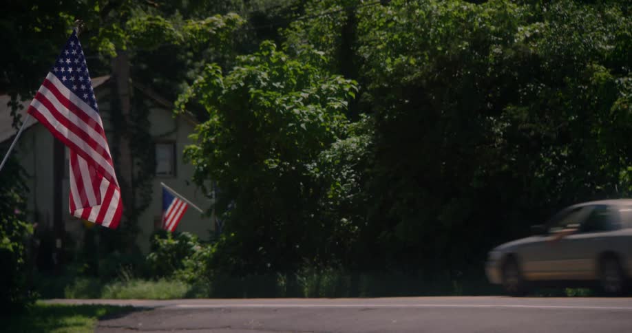 Cars drive past flags on a road