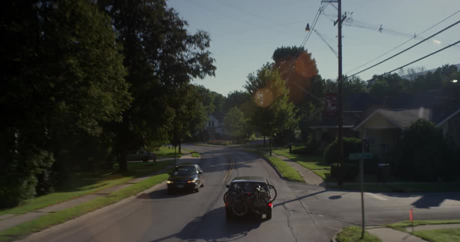 An suv carrying bicycles drives down a suburban street