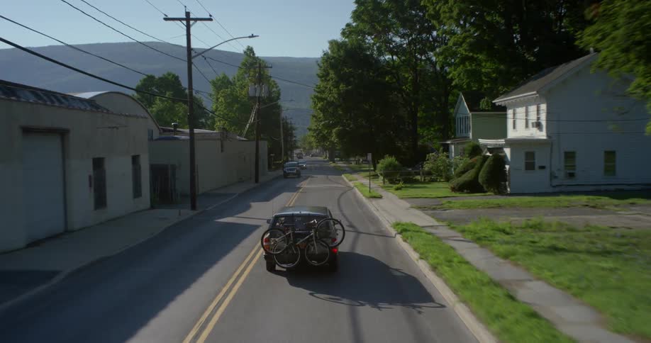 An suv with bikes on the back drives down a road